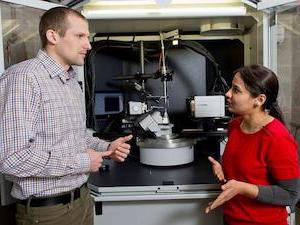 Professor and student standing in lab, discussing research.